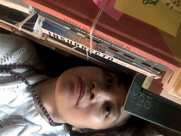 Angela, nestled against her to-read pile Angela, nestled against her to-read pile